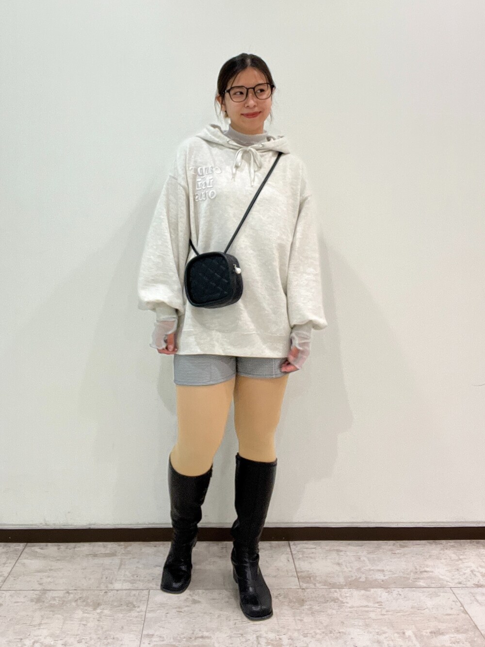 ブラック系のショルダーバッグ、ベージュ系のパーカー、ホワイト系のTシャツ/カットソーを着用したレディースの冬コーディネートの2枚目の写真