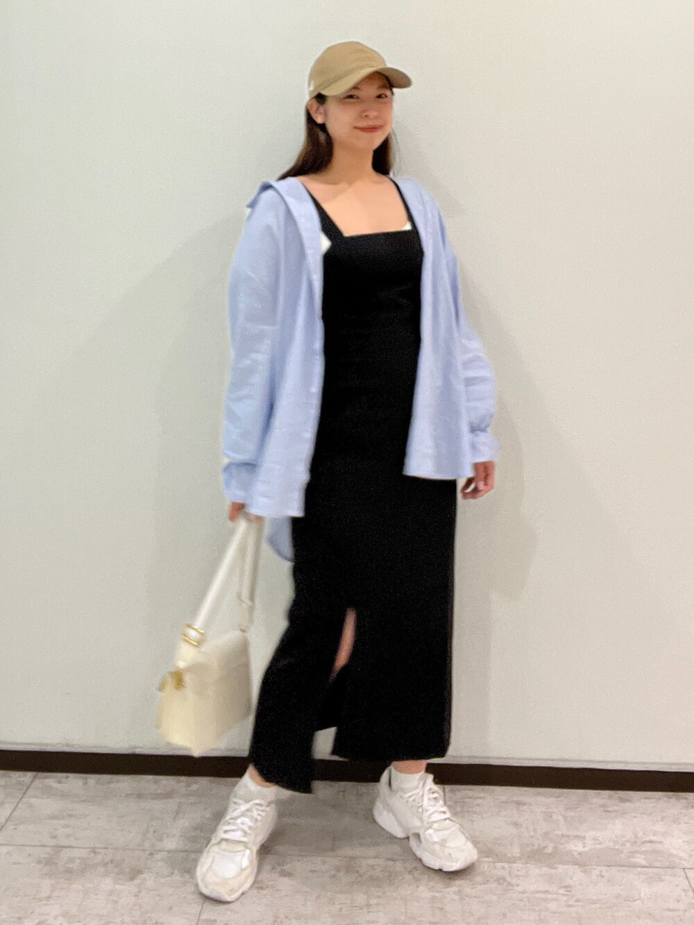 ブルー系のシャツ/ブラウス、ブラック系のジャンパースカート、ホワイト系のショルダーバッグを着用したレディースの春コーディネートの2枚目の写真