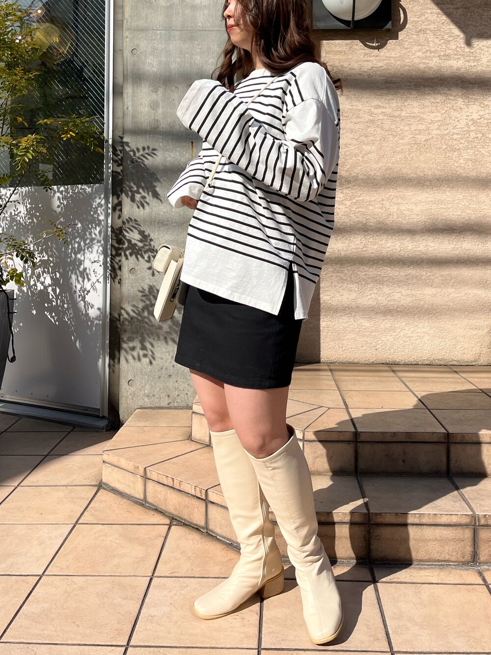 ブラック系のTシャツ/カットソー、ホワイト系のショルダーバッグ、ブラック系のスカートを着用したレディースの冬コーディネートの2枚目の写真