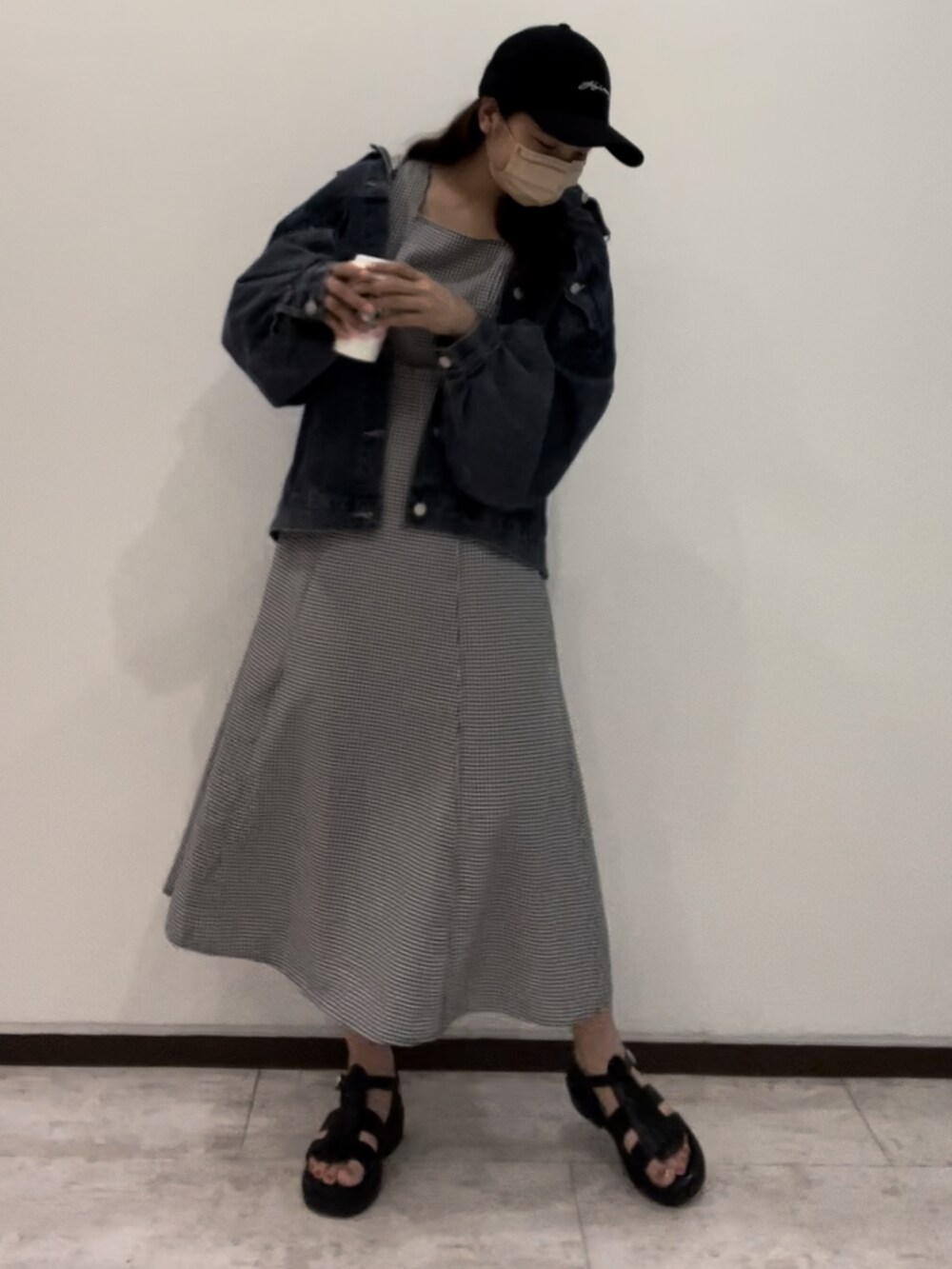 ブルー系のデニムジャケット、ブラック系のワンピース、ブラック系のサンダルを着用したレディースの春コーディネートの2枚目の写真