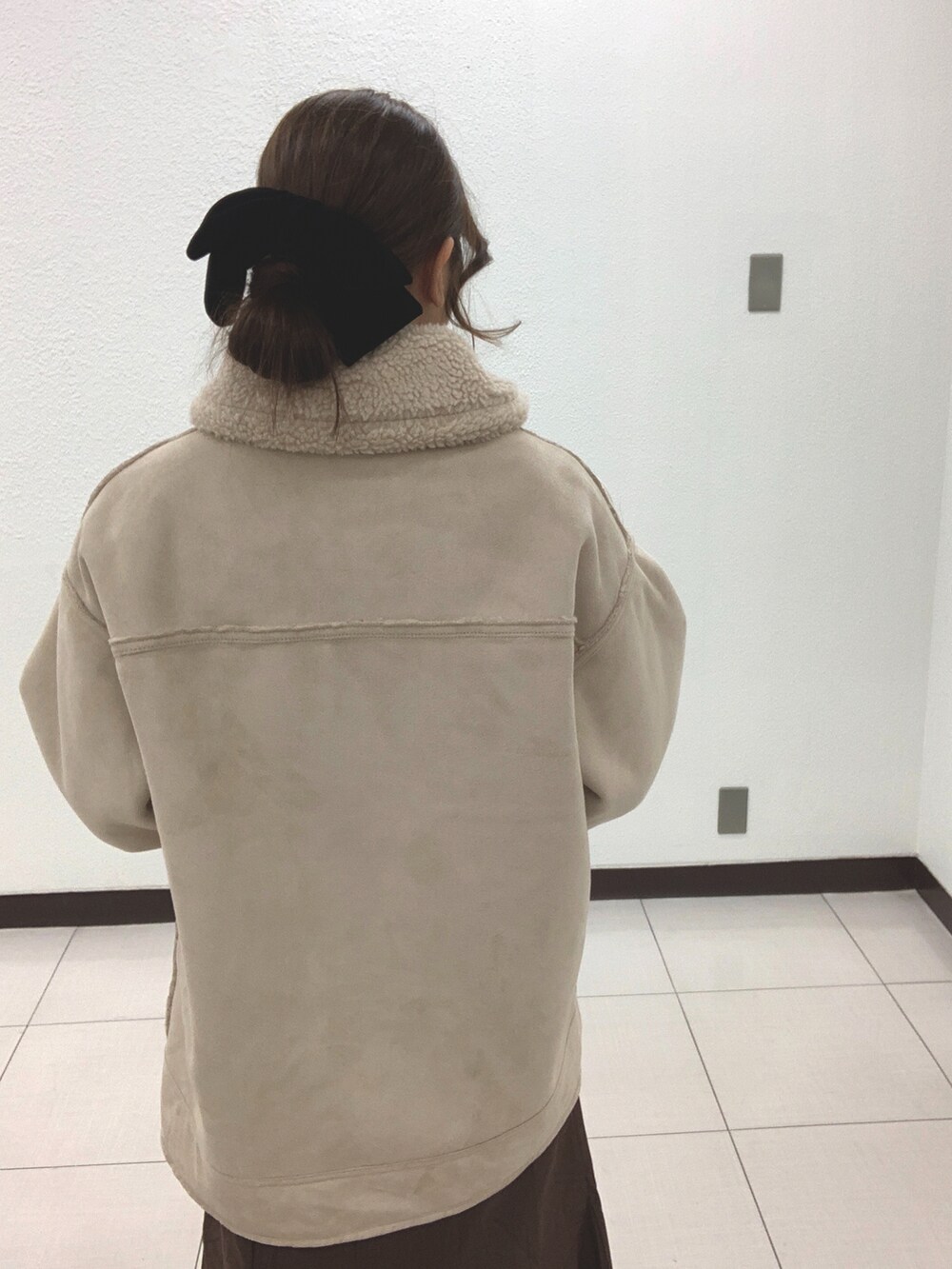 ベージュ系のムートンコート、ブラウン系のスカートを着用したレディースの冬コーディネートの2枚目の写真