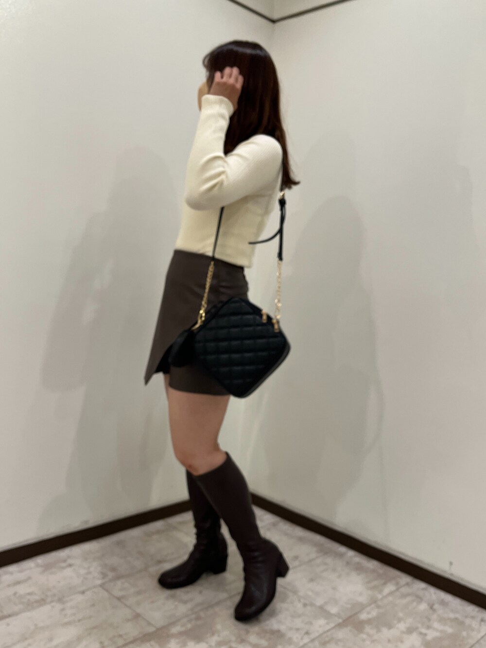 ホワイト系のニット/セーター、ブラウン系のスカート、ブラック系のショルダーバッグを着用したレディースの秋コーディネートの4枚目の写真