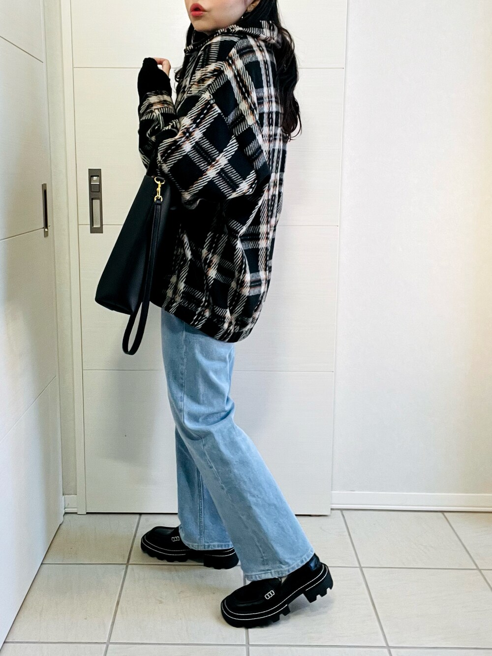 ブラック系のブルゾン、ブラック系のニット/セーター、ブルー系のデニムパンツを着用したレディースの冬コーディネートの4枚目の写真