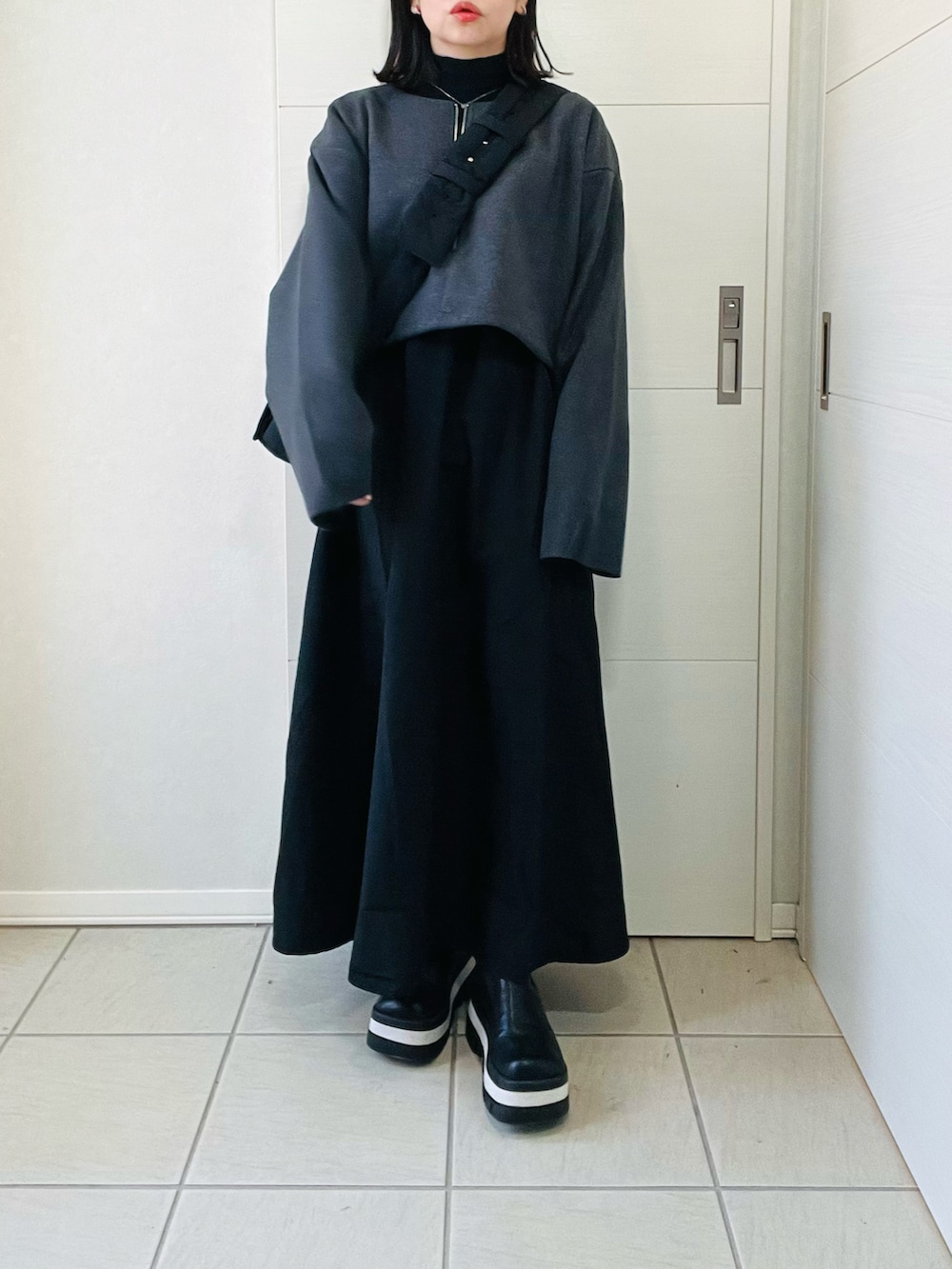 ブラック系のワンピース、ブラック系のショルダーバッグ、ブラック系のブーツを着用したレディースの秋コーディネートの5枚目の写真