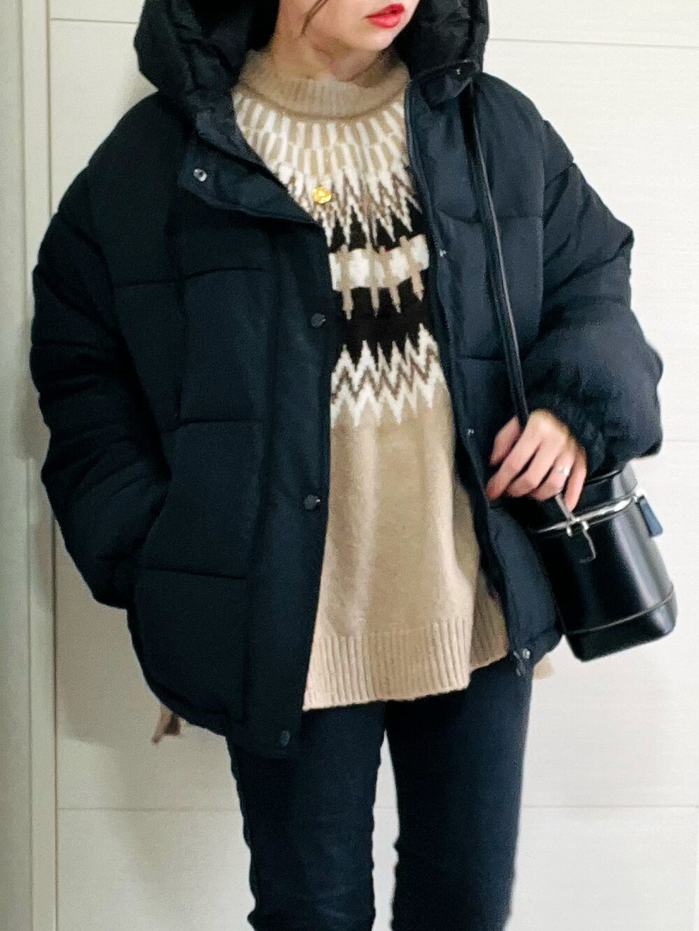 ブラック系のダウンジャケット/コート、ベージュ系のニット/セーター、ブラック系のデニムパンツを着用したレディースの冬コーディネートの2枚目の写真