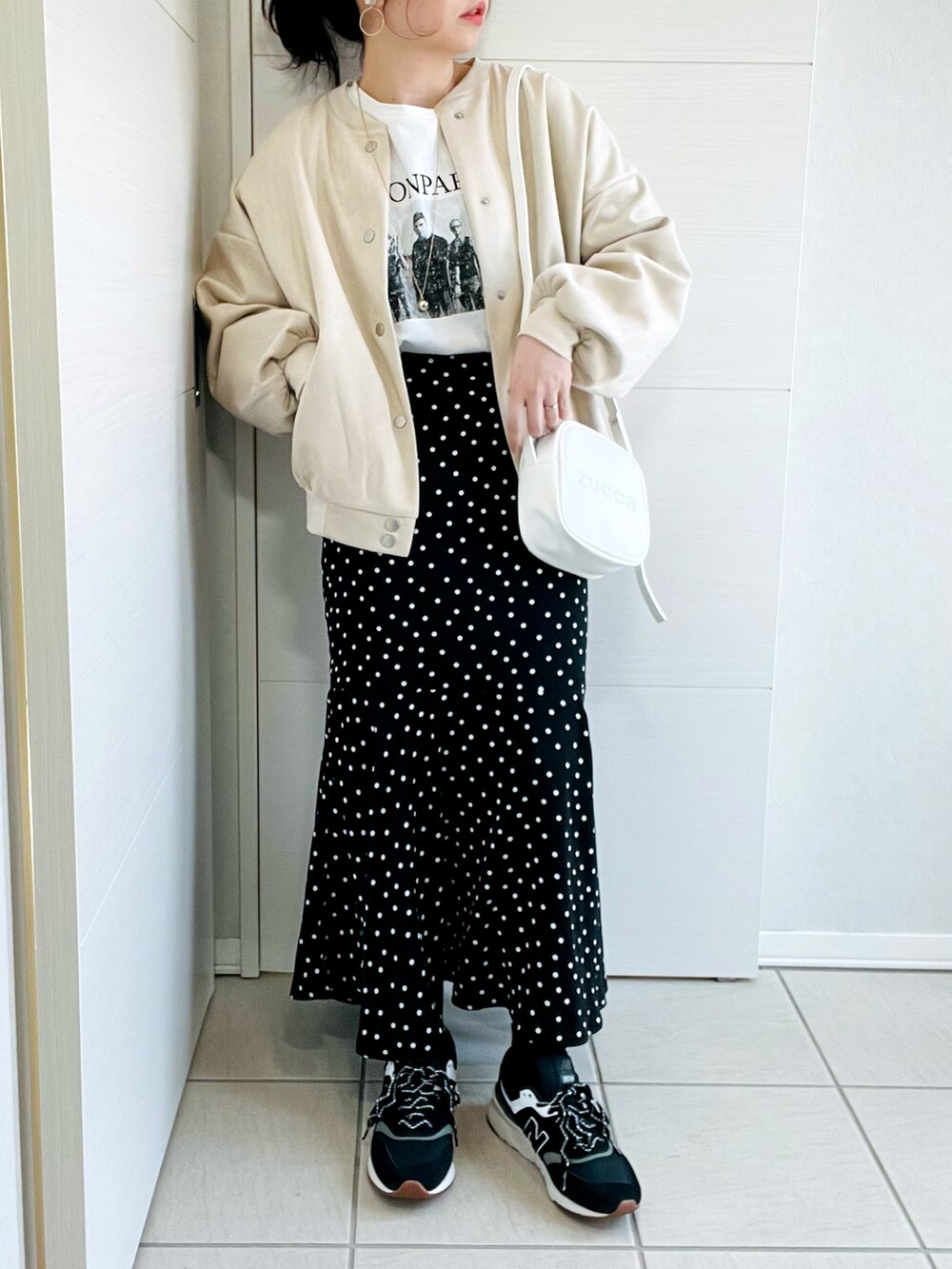 ホワイト系のスタジャン、ホワイト系のTシャツ/カットソー、ブラック系のスカートを着用したレディースの春コーディネートの2枚目の写真