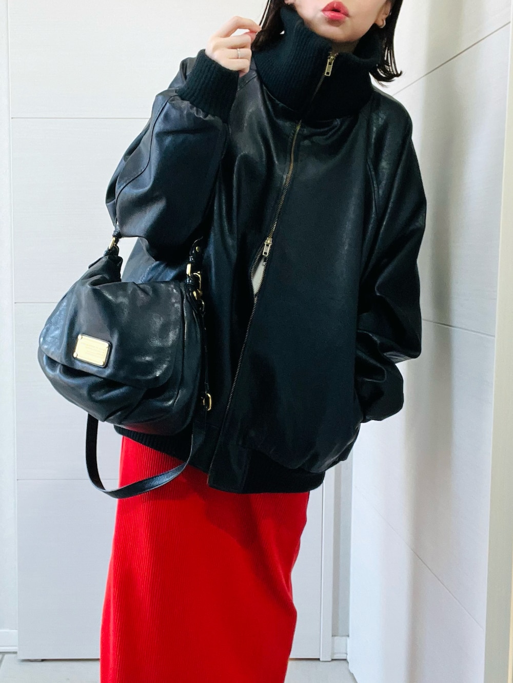 ブラック系のブルゾン、ホワイト系のニット/セーター、オレンジ系のスカートを着用したレディースの冬コーディネートの3枚目の写真