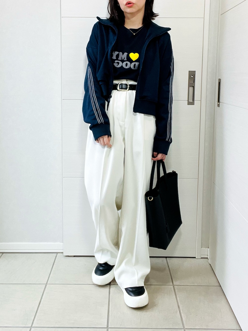 ブルー系のブルゾン、ホワイト系のスラックス、ブラック系のスニーカーを着用したレディースの秋コーディネートの4枚目の写真