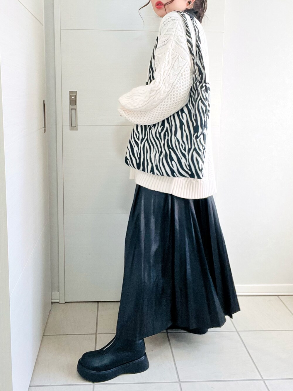 ホワイト系のニット/セーター、ブラック系のTシャツ/カットソー、ブラック系のスカートを着用したレディースの秋コーディネートの5枚目の写真