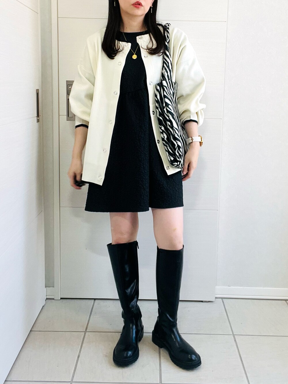 ホワイト系のカーディガン/ボレロ、ブラック系のシャツ/ブラウス、ブラック系のブーツを着用したレディースの秋コーディネートの2枚目の写真