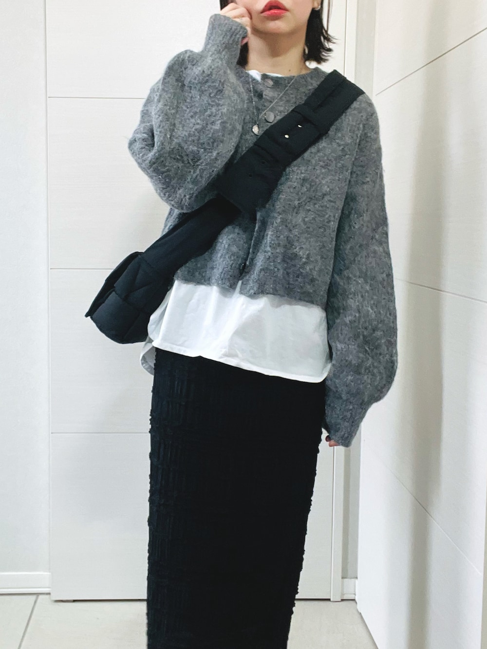 グレー系のカーディガン/ボレロ、ホワイト系のTシャツ/カットソー、ブラック系のスカートを着用したレディースの冬コーディネートの2枚目の写真