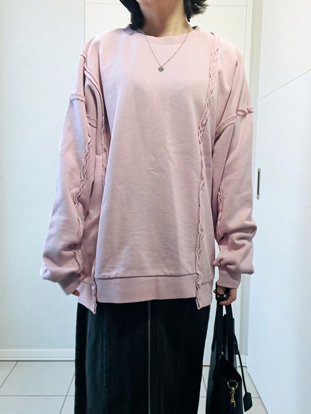 ピンク系のスウェット、ブラック系のスカート、ブラック系のブーツを着用したレディースの冬コーディネートの2枚目の写真