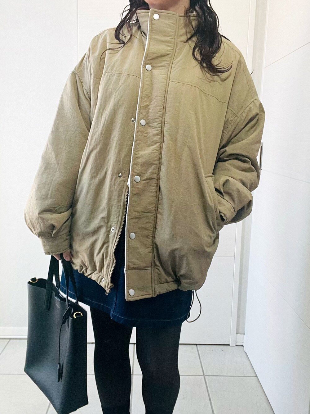 ベージュ系のブルゾン、ホワイト系のニット/セーター、ブルー系のデニムスカートを着用したレディースの秋コーディネートの3枚目の写真