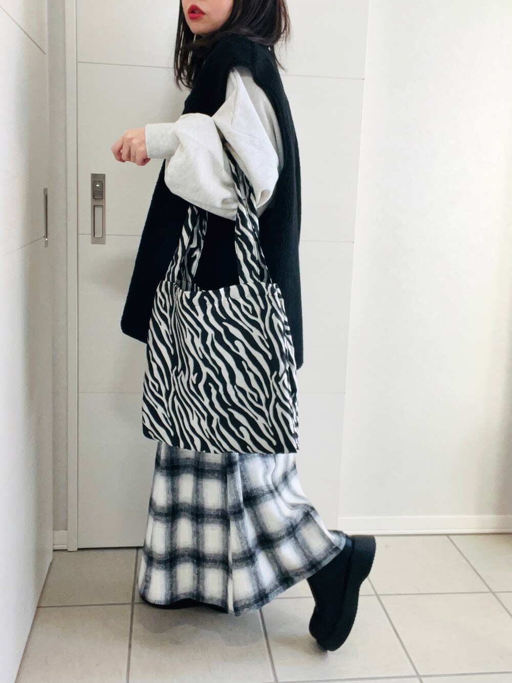 ブラック系のベスト、グレー系のスウェット、ホワイト系のスカートを着用したレディースの冬コーディネートの4枚目の写真