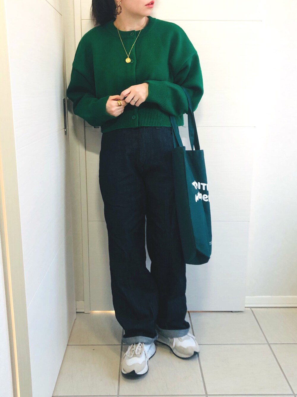 ブラック系のノーカラーコート、グリーン系のカーディガン/ボレロ、ブルー系のセットアップを着用したレディースの冬コーディネートの3枚目の写真