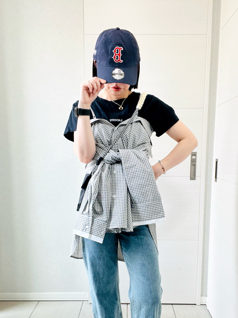 ホワイト系のシャツ/ブラウス、ブラック系のスニーカー、ブルー系のデニムパンツを着用したレディースの夏コーディネートの2枚目の写真