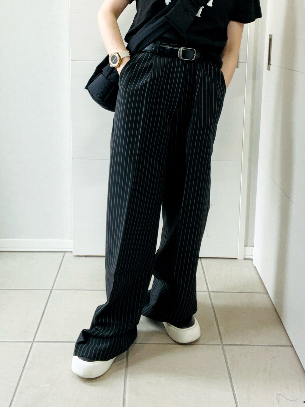 ブラック系のデニムパンツ、ブラック系のTシャツ/カットソー、ブラック系のスニーカーを着用したレディースの秋コーディネートの3枚目の写真