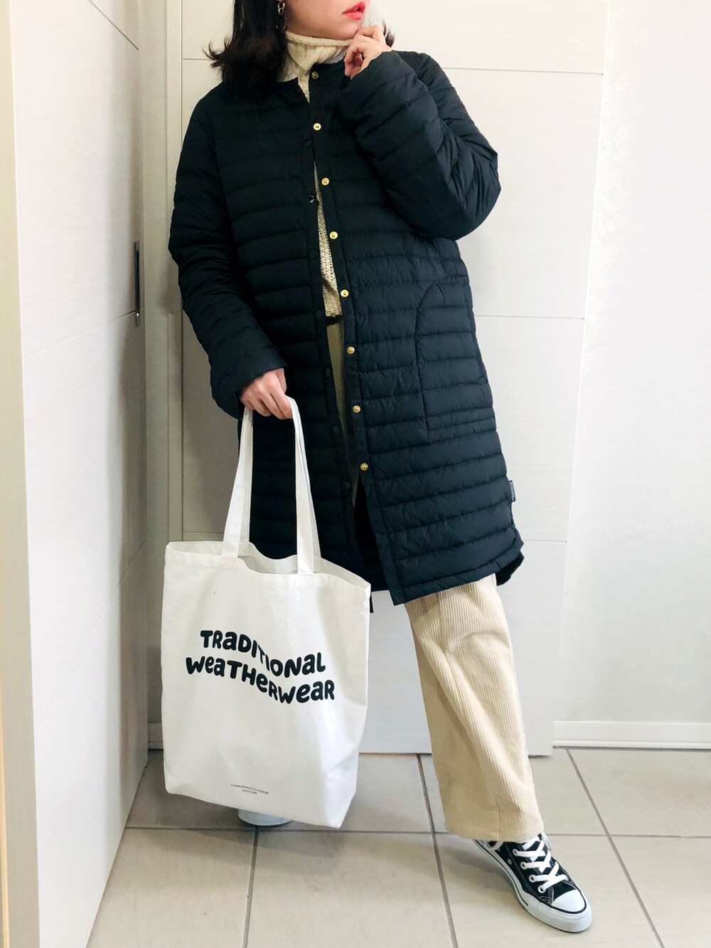 ブラック系のダウンジャケット/コート、ホワイト系のニット/セーター、ベージュ系のその他パンツを着用したレディースの冬コーディネートの2枚目の写真