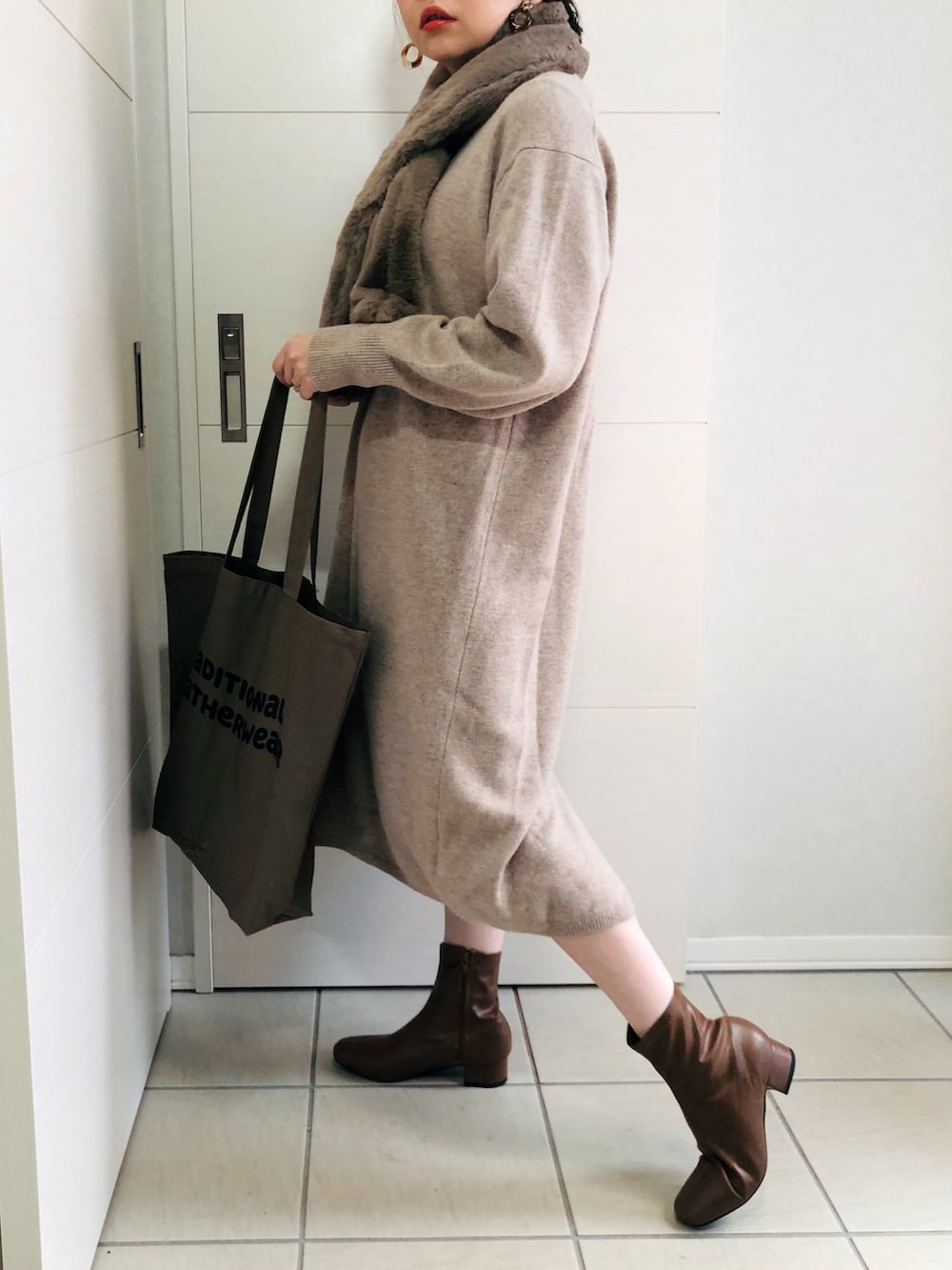 ホワイト系のノーカラーコート、ベージュ系のワンピース、ブラウン系のブーツを着用したレディースの秋コーディネートの3枚目の写真