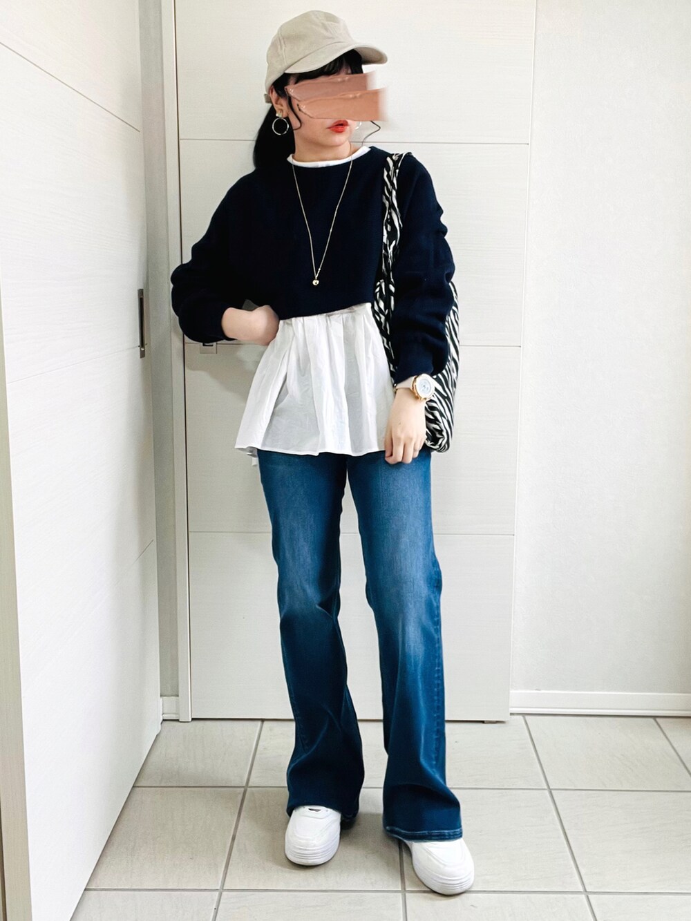 ブルー系のニット/セーター、ブルー系のデニムパンツ、ホワイト系のスニーカーを着用したレディースの春コーディネートの4枚目の写真