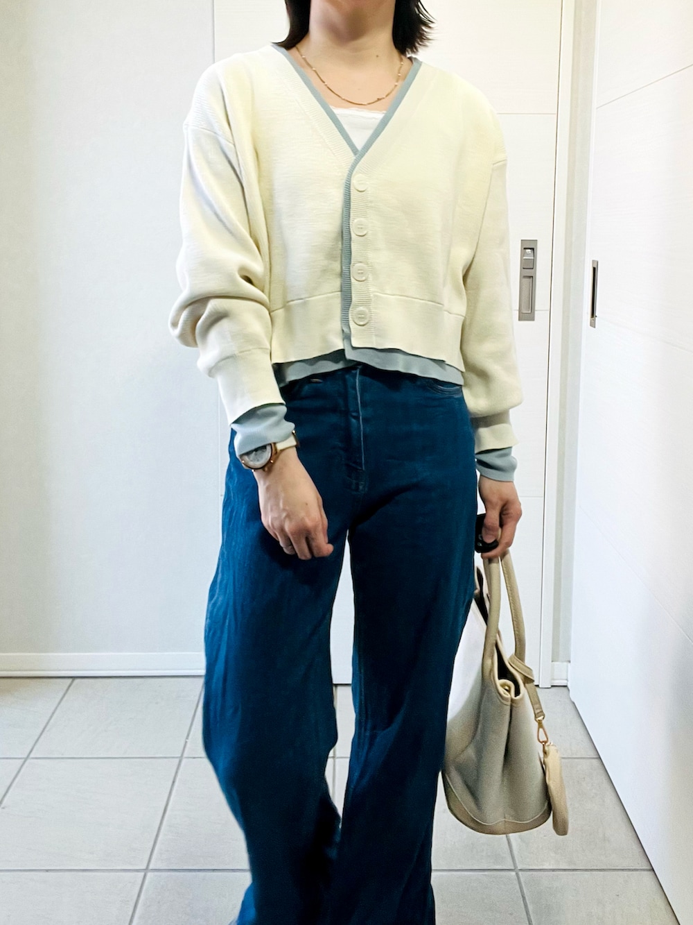 ホワイト系のカーディガン/ボレロ、グレー系のスニーカー、ブルー系のデニムパンツを着用したレディースの春コーディネートの2枚目の写真