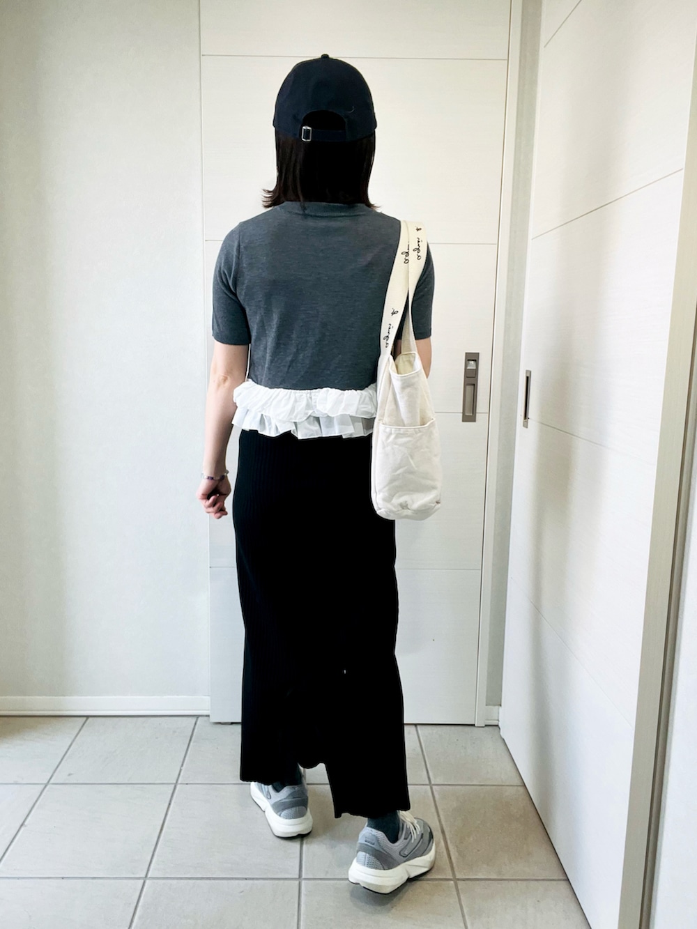 グレー系のカーディガン/ボレロ、ブラック系のスカート、グレー系のスニーカーを着用したレディースの春コーディネートの5枚目の写真
