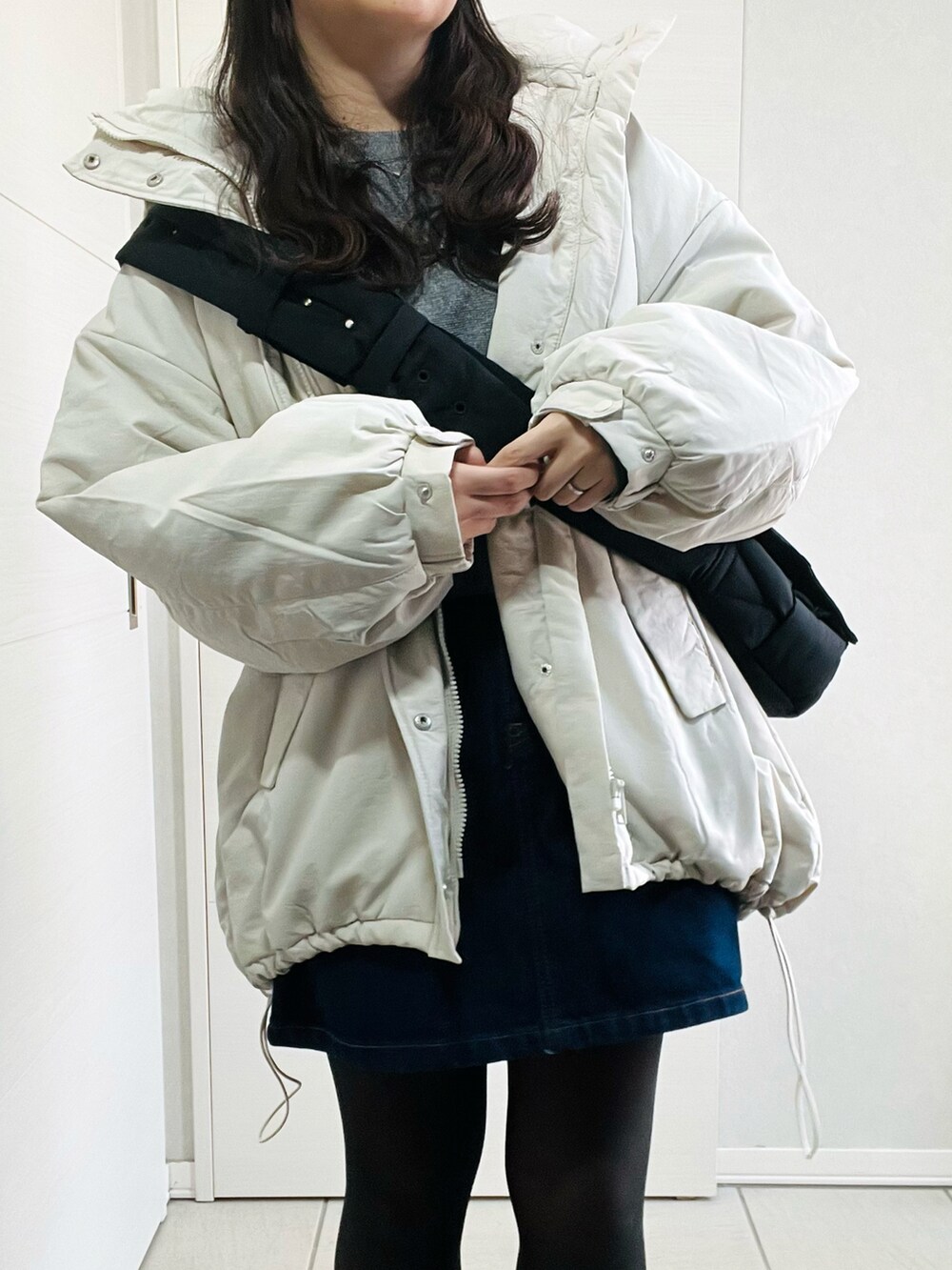 ホワイト系のダウンジャケット/コート、グレー系のニット/セーター、ブルー系のデニムスカートを着用したレディースの冬コーディネートの2枚目の写真