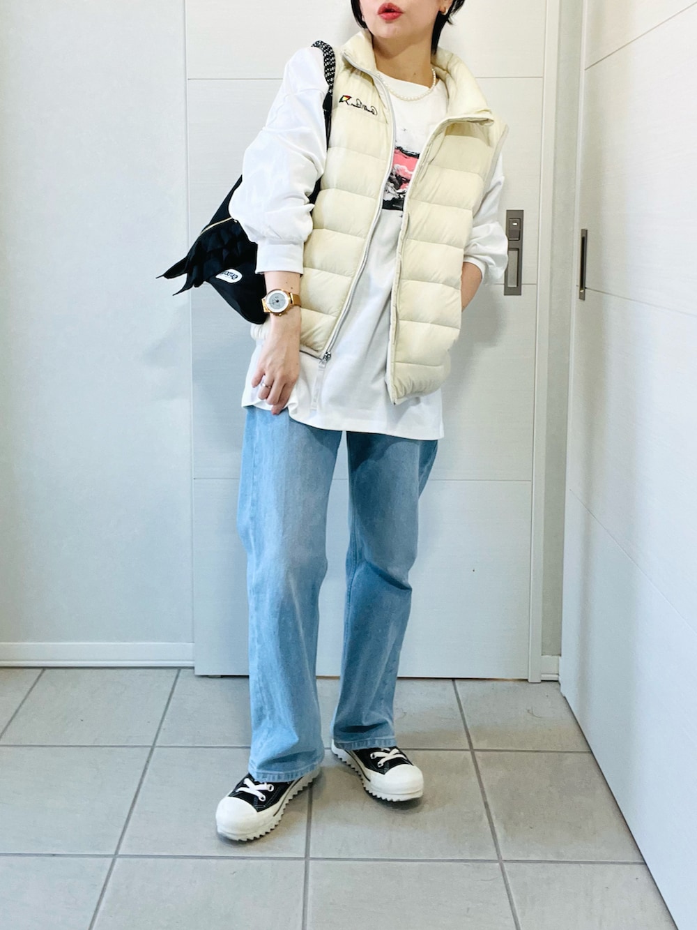 ホワイト系のダウンベスト、ホワイト系のTシャツ/カットソー、ブルー系のデニムパンツを着用したレディースの秋コーディネートの3枚目の写真