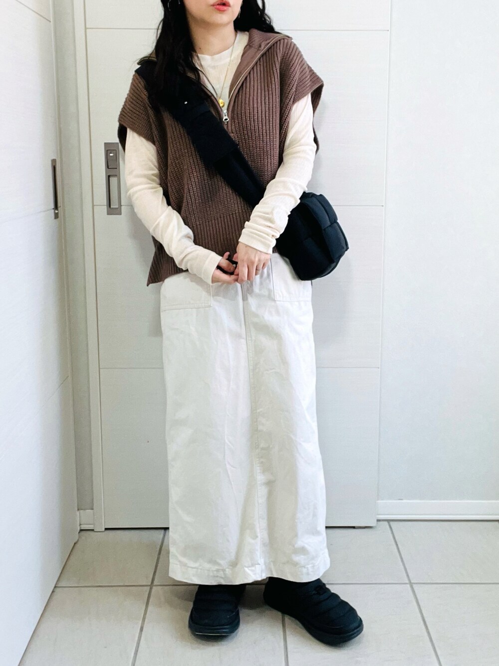 ブラウン系のベスト、ホワイト系のTシャツ/カットソー、ホワイト系のスカートを着用したレディースの秋コーディネートの2枚目の写真