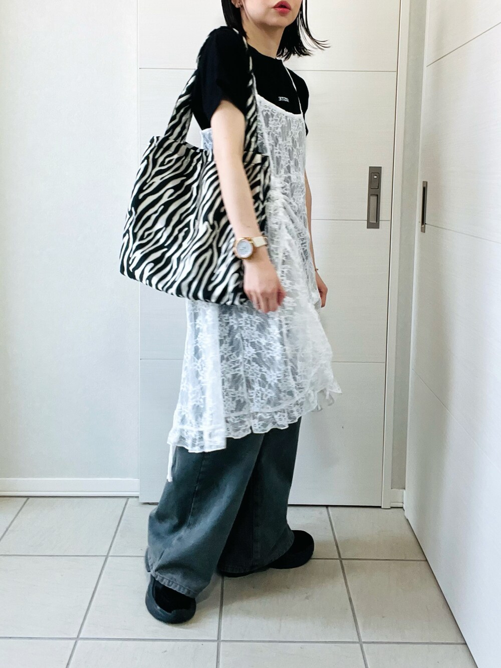 ホワイト系のチュニック、ブラック系のTシャツ/カットソー、ブルー系のデニムパンツを着用したレディースの春コーディネートの3枚目の写真