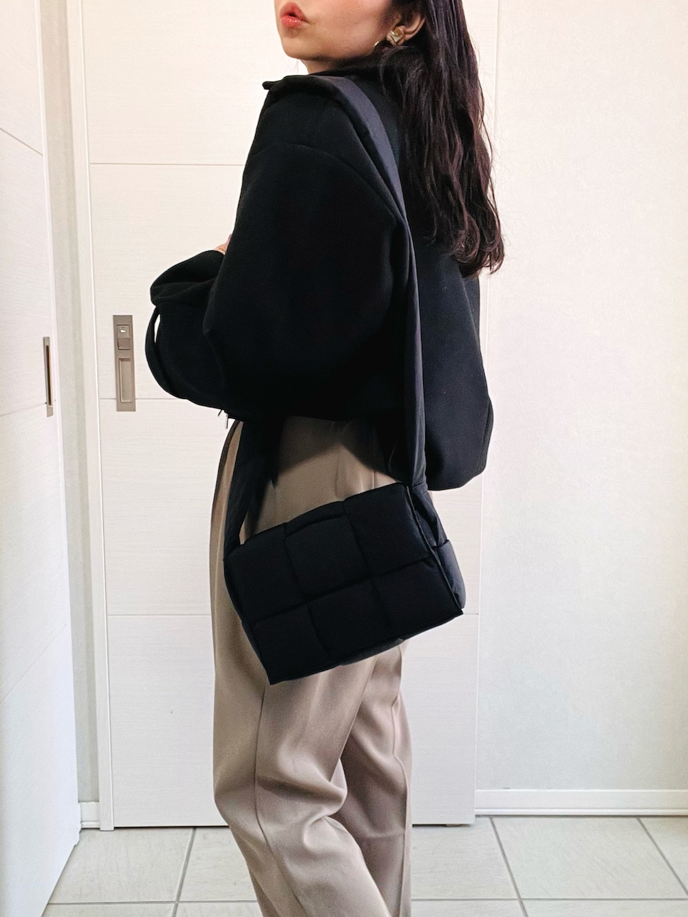 ブラック系のブルゾン、ホワイト系のニット/セーター、ベージュ系のスラックスを着用したレディースの秋コーディネートの4枚目の写真