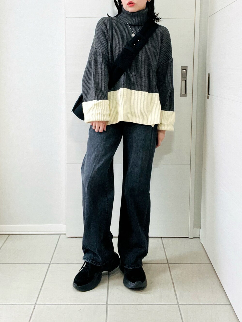 グレー系のニット/セーター、ブラック系のデニムパンツ、ブラック系のスニーカーを着用したレディースの冬コーディネートの2枚目の写真