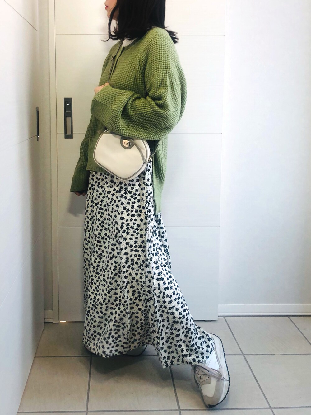 グリーン系のニット/セーター、ホワイト系のスカート、ホワイト系のスニーカーを着用したレディースの冬コーディネートの2枚目の写真