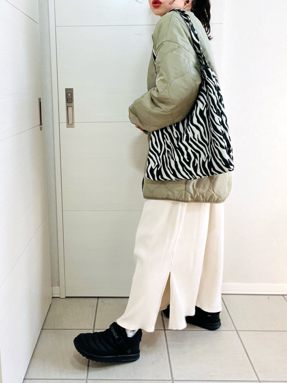 グリーン系のノーカラージャケット、ホワイト系のワンピース、ブラック系のスニーカーを着用したレディースの冬コーディネートの5枚目の写真