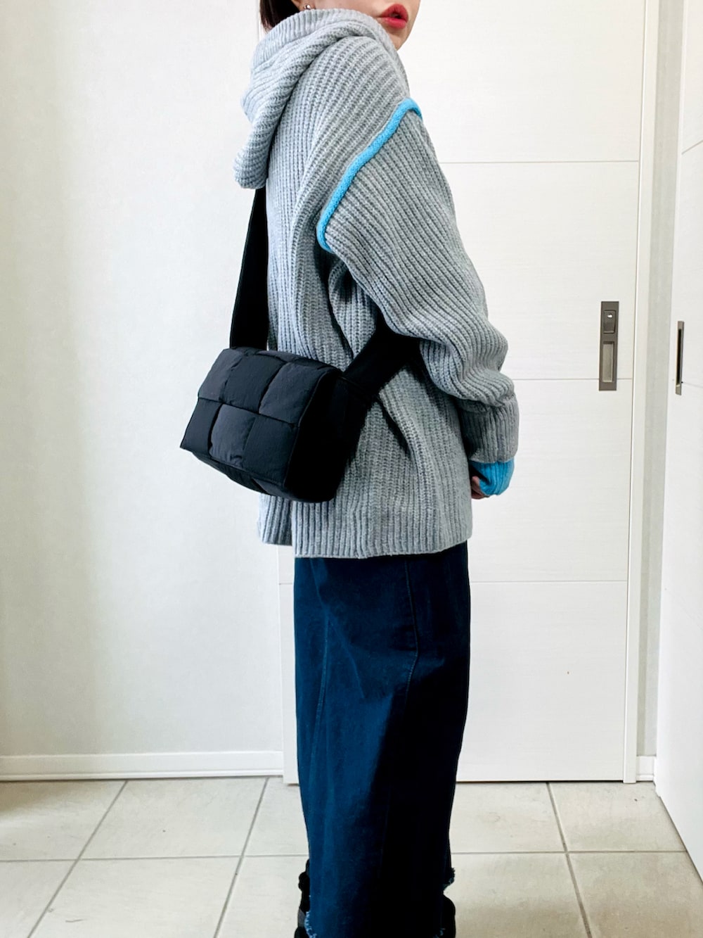 グレー系のニット/セーター、ブルー系のスカート、ブラック系のブーツを着用したレディースの冬コーディネートの3枚目の写真