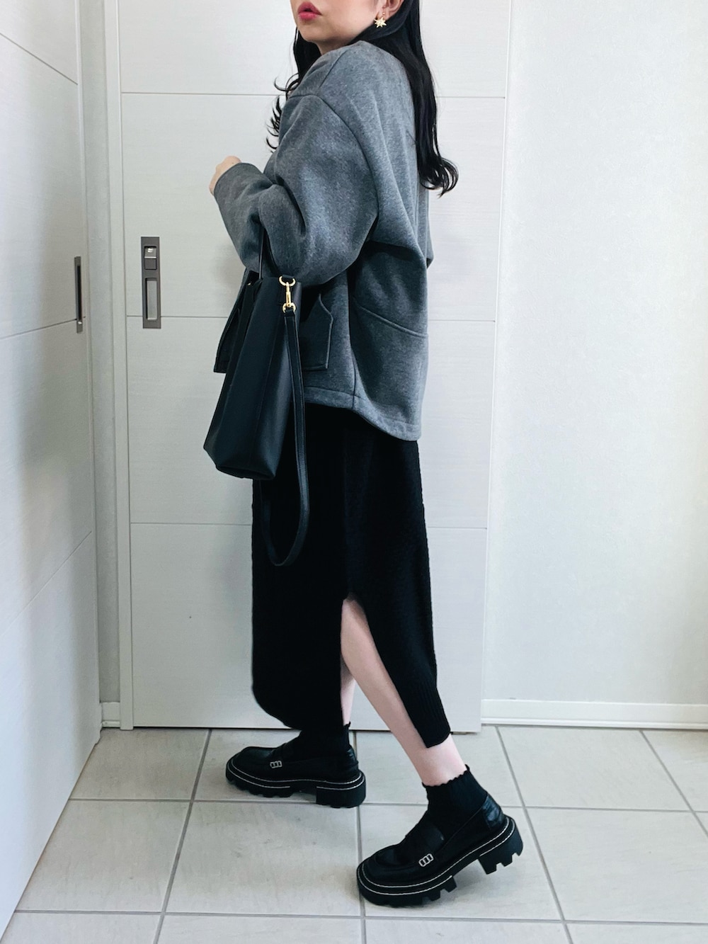 ブラック系のワンピース、グレー系のブルゾン、ブラック系のローファーを着用したレディースの秋コーディネートの2枚目の写真