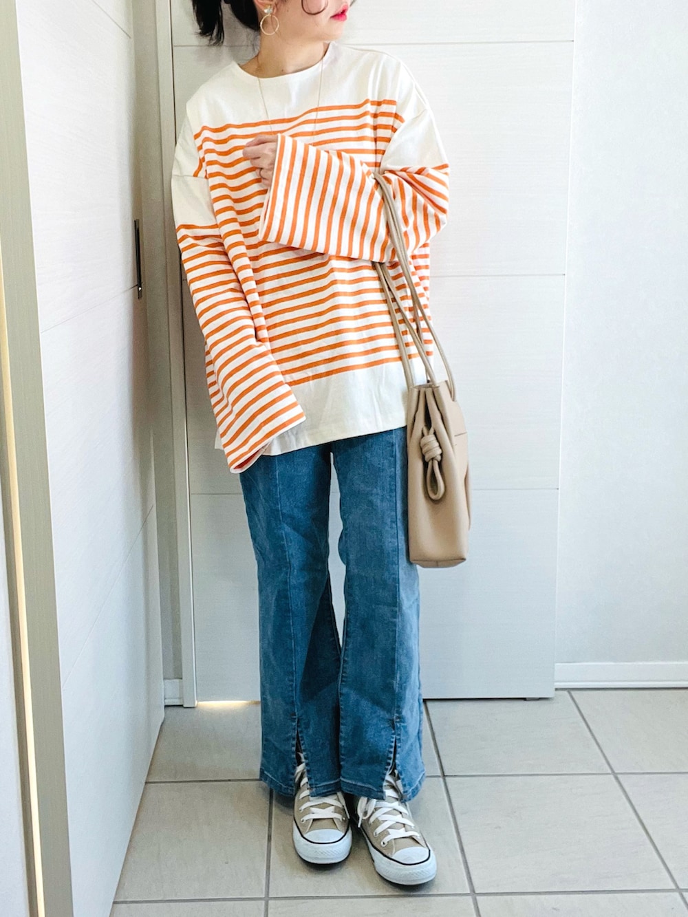 オレンジ系のTシャツ/カットソー、ブルー系のデニムパンツ、ベージュ系のトートバッグを着用したレディースの冬コーディネートの4枚目の写真