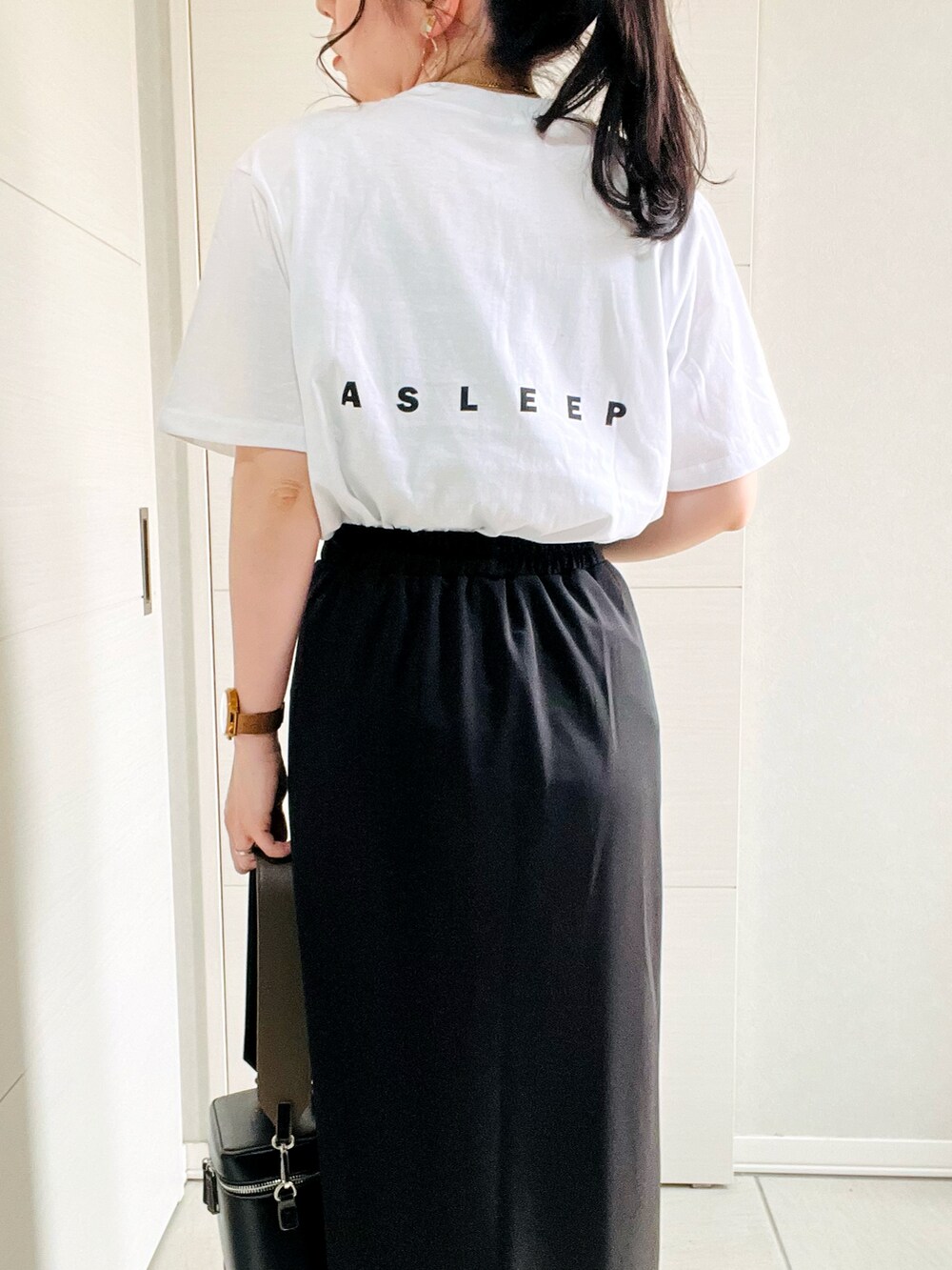 ホワイト系のTシャツ/カットソー、ブラック系のスカート、ブラック系のスニーカーを着用したレディースの春コーディネートの3枚目の写真