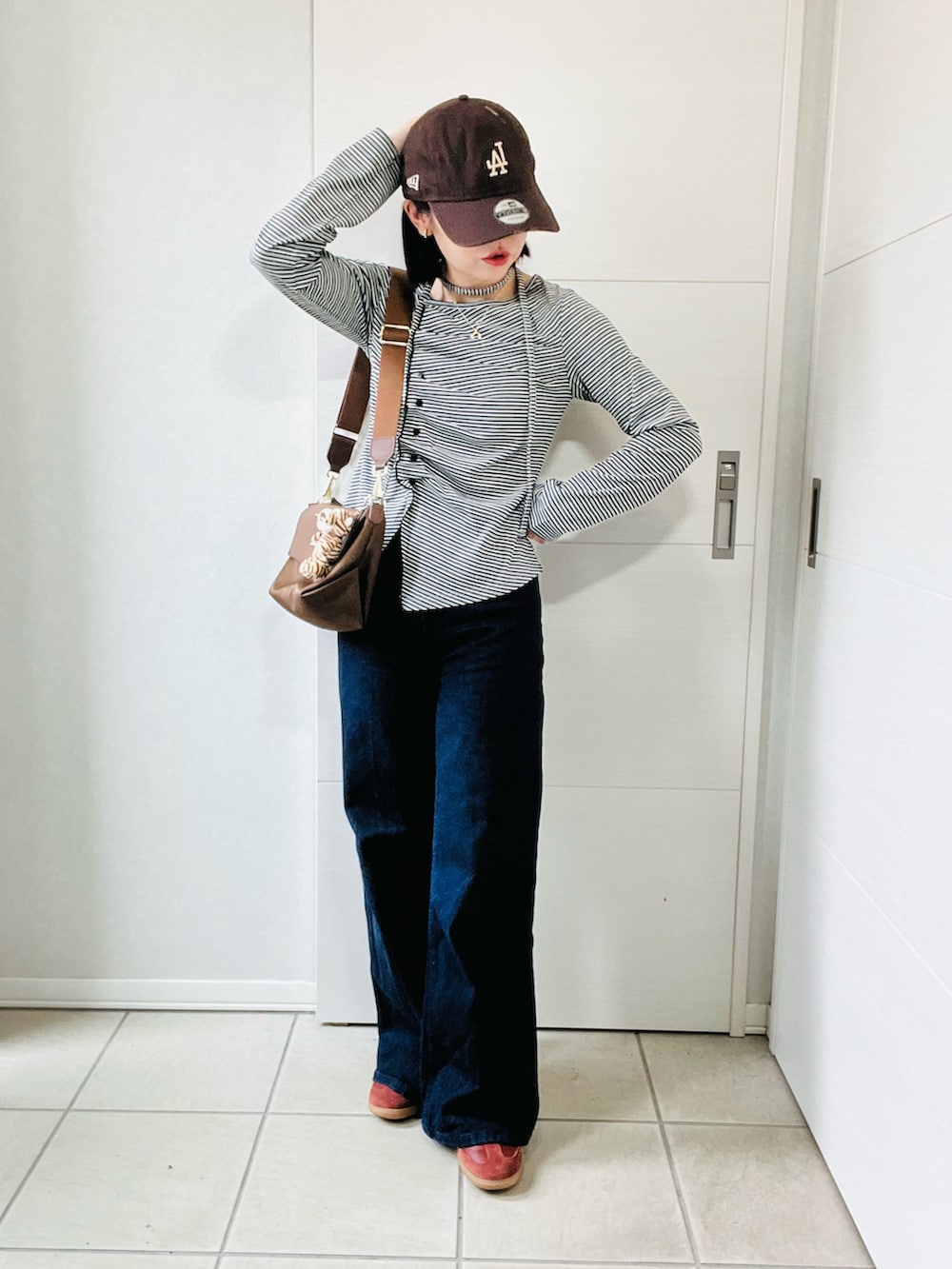 ブラック系のTシャツ/カットソー、ブラウン系のスニーカー、ブルー系のデニムパンツを着用したレディースの秋コーディネートの4枚目の写真