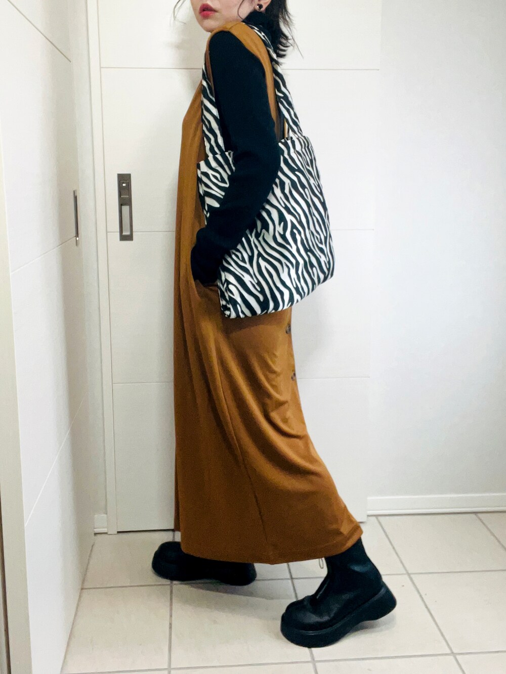 ブラウン系のサロペット/オーバーオール、ブラック系のニット/セーター、ブラック系のブーツを着用したレディースの秋コーディネートの5枚目の写真