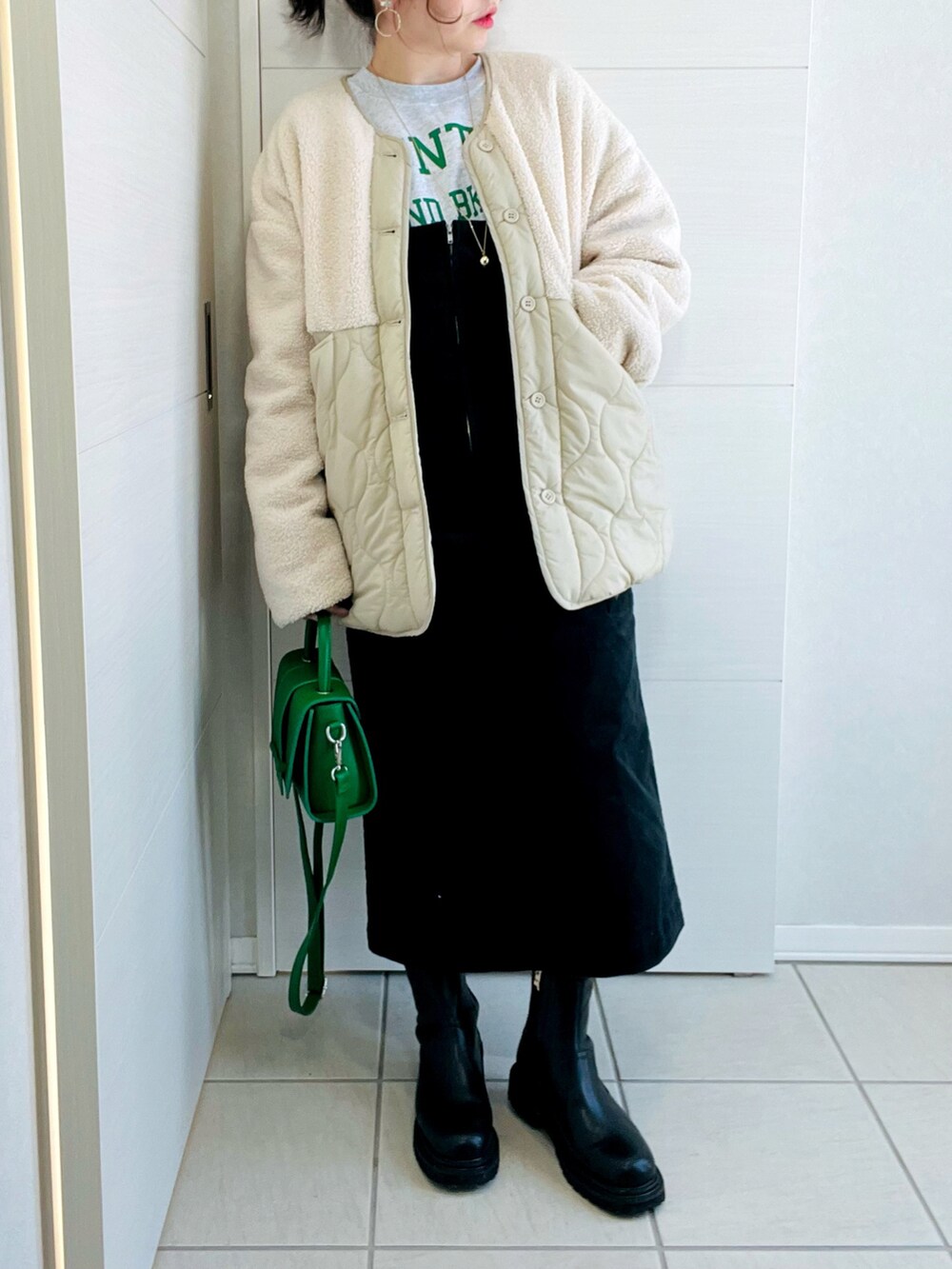 ホワイト系のその他アウター、グレー系のスウェット、ブラック系のジャンパースカートを着用したレディースの冬コーディネートの2枚目の写真