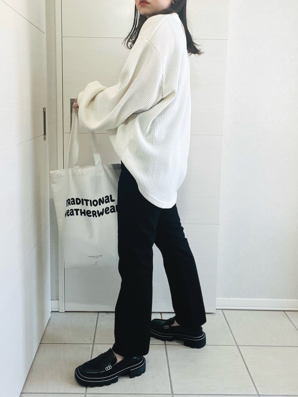 ホワイト系のトレンチコート、ホワイト系のスウェット、ブラック系のパンツを着用したレディースの春コーディネートの5枚目の写真