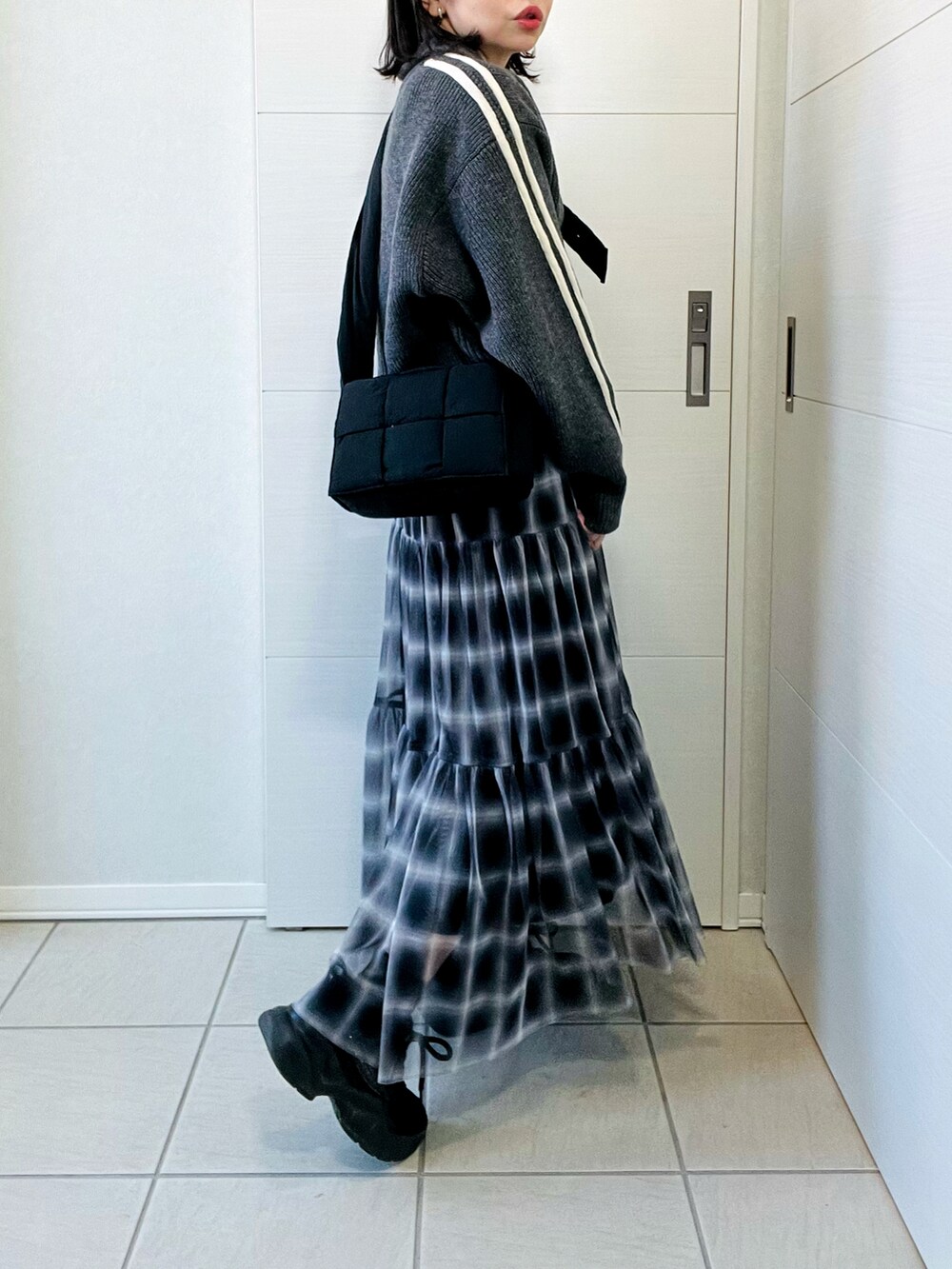 グレー系のニット/セーター、ブラック系のスカート、ブラック系のスニーカーを着用したレディースの冬コーディネートの4枚目の写真