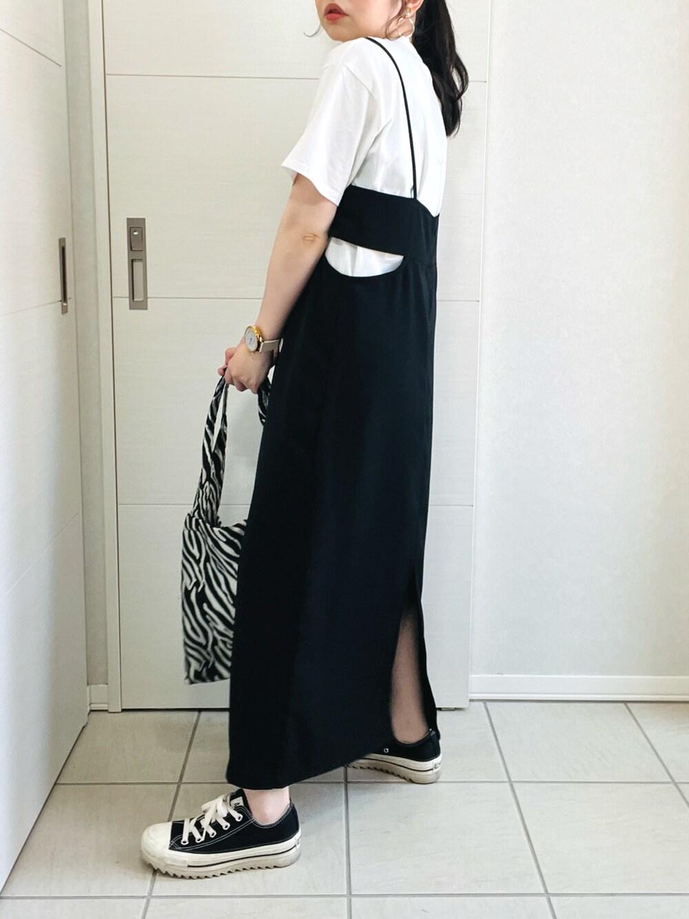 ホワイト系のTシャツ/カットソー、ブラック系のジャンパースカート、ブラック系のスニーカーを着用したレディースの春コーディネートの5枚目の写真