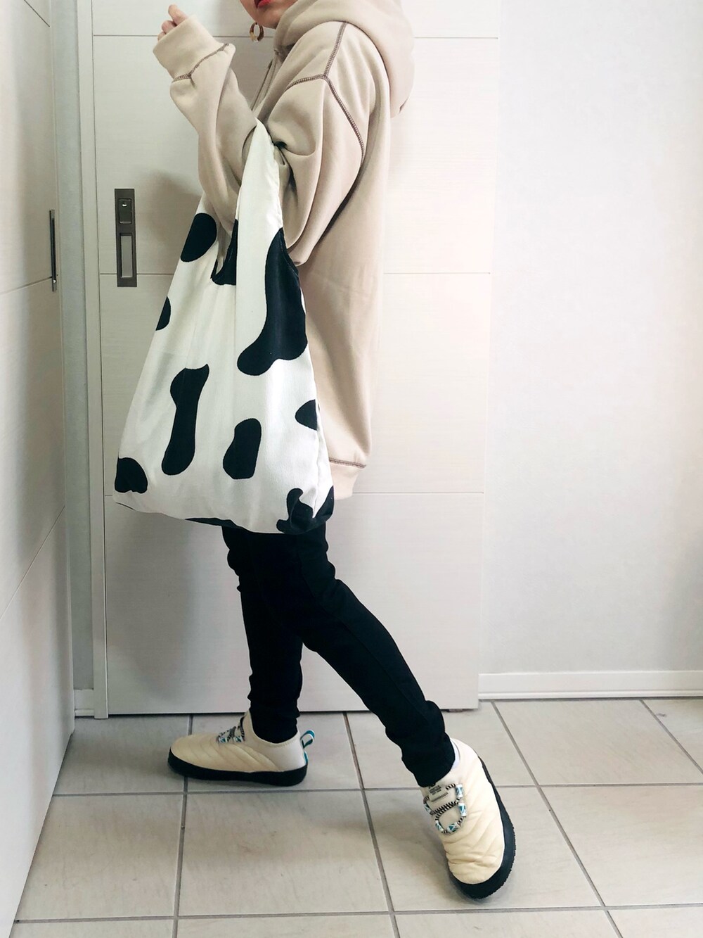 ベージュ系のパーカー、ブラック系のデニムパンツ、ホワイト系のスリッポンを着用したレディースの秋コーディネートの3枚目の写真