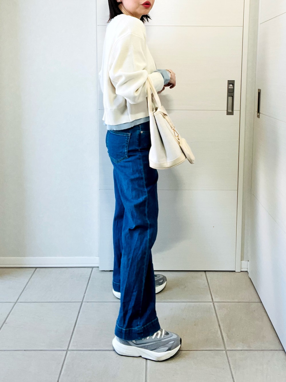 ホワイト系のカーディガン/ボレロ、グレー系のスニーカー、ブルー系のデニムパンツを着用したレディースの春コーディネートの5枚目の写真