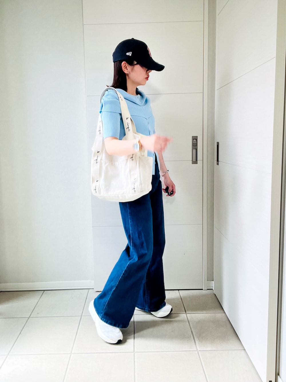 ホワイト系のスニーカー、ブルー系のニット/セーター、ベージュ系のトートバッグを着用したレディースの夏コーディネートの3枚目の写真