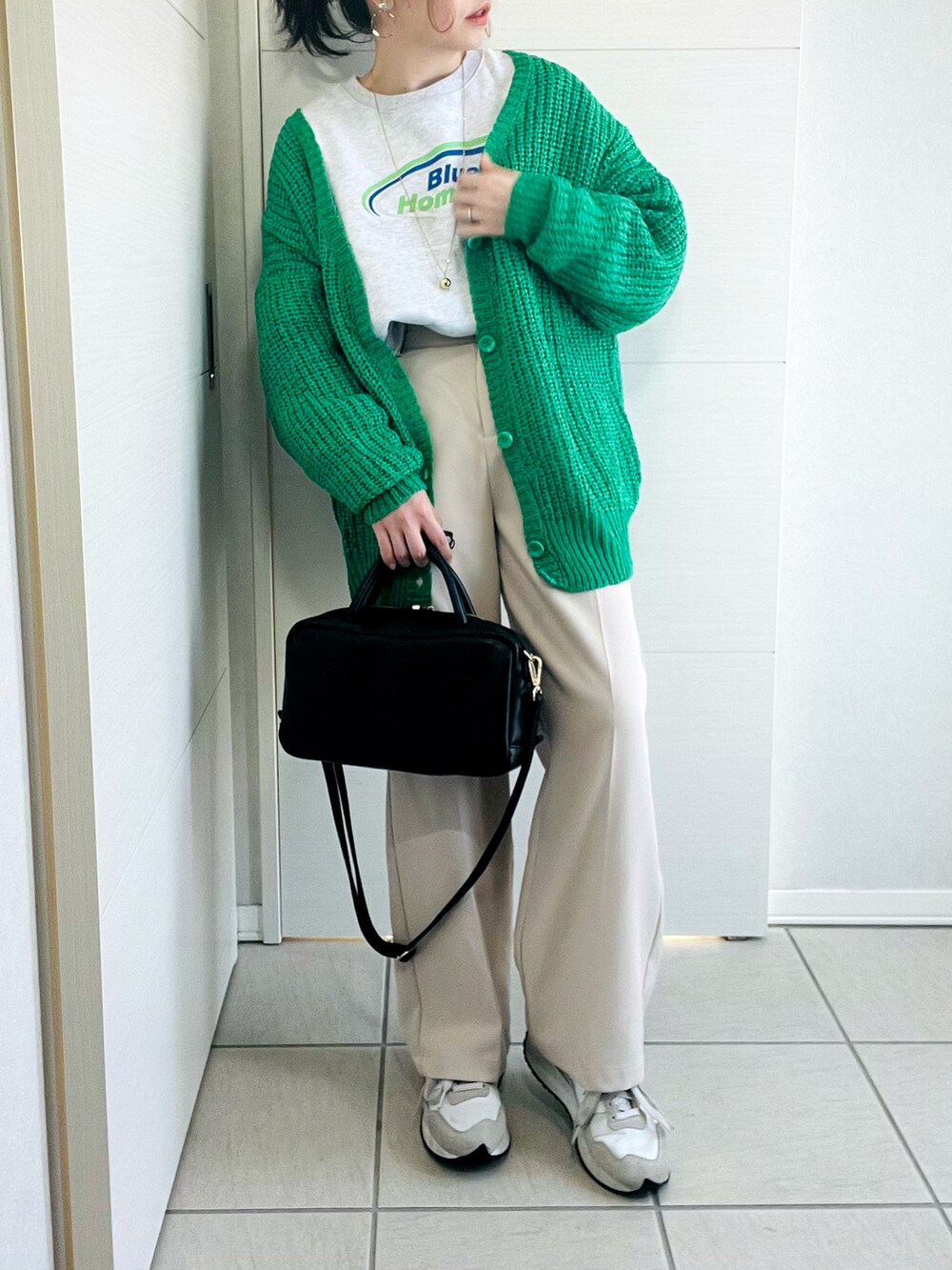 グレー系のスウェット、グリーン系のカーディガン/ボレロ、ホワイト系のスラックスを着用したレディースの春コーディネートの2枚目の写真