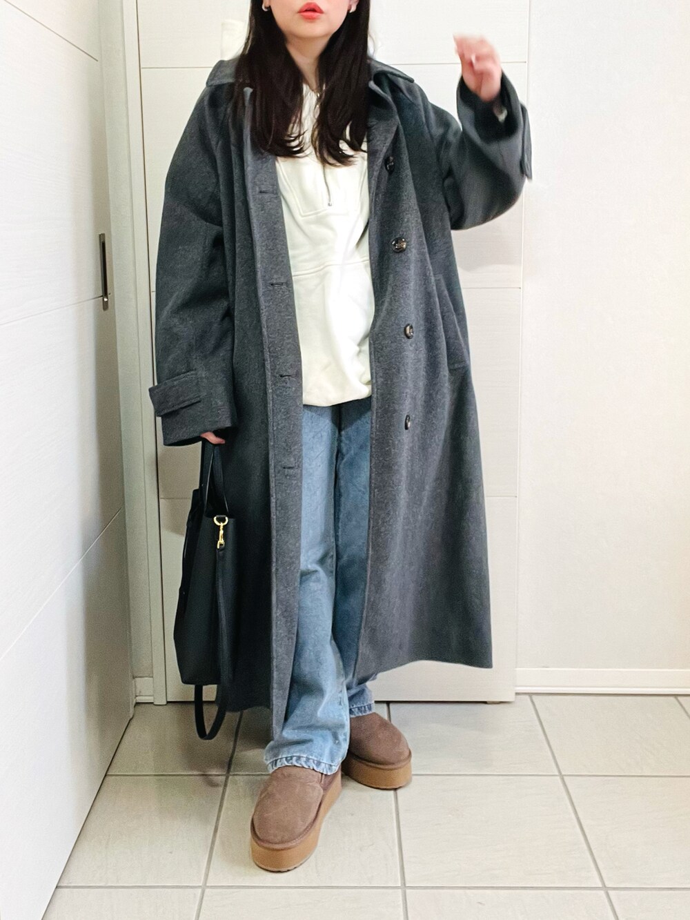 ホワイト系のパーカー、グレー系のステンカラーコート、ブルー系のデニムパンツを着用したレディースの冬コーディネートの2枚目の写真