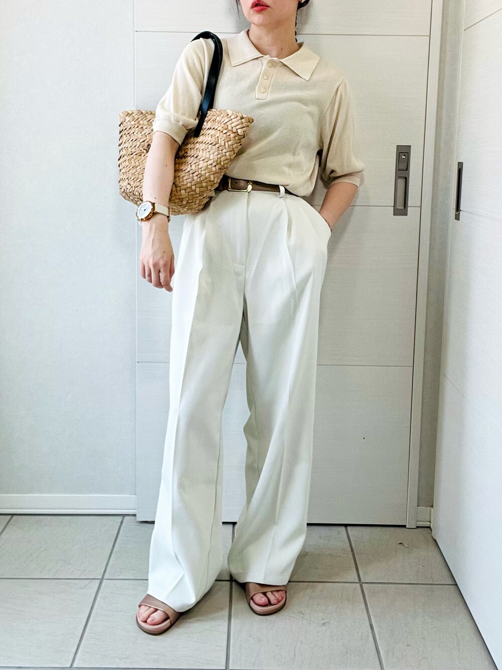 ホワイト系のポロシャツ、ホワイト系のスラックス、ブラック系のかごバッグを着用したレディースの夏コーディネートの3枚目の写真